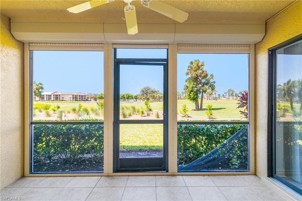 Doorway to outside featuring a textured wall, tile patterned floors, a textured ceiling, plenty of natural light, and golf course view