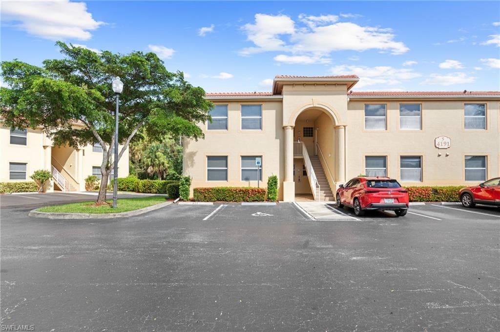 View of property featuring stairway and uncovered parking