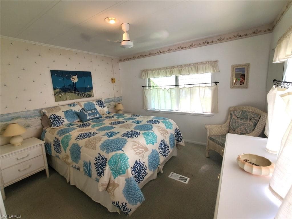 Primary bedroom with neutral carpet and ceiling fan.