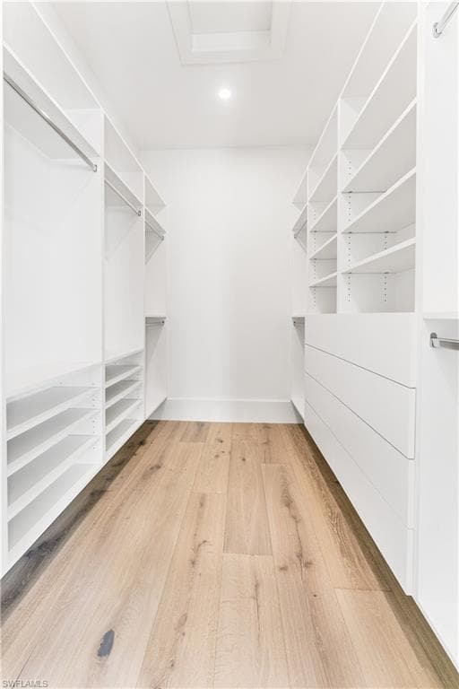 Walk in closet with light wood finished floors