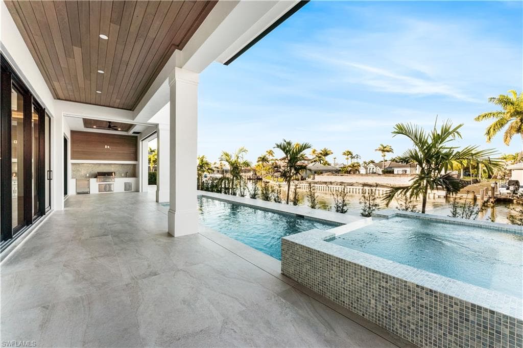 Outdoor pool with an in-ground hot tub, a patio, and an outdoor kitchen