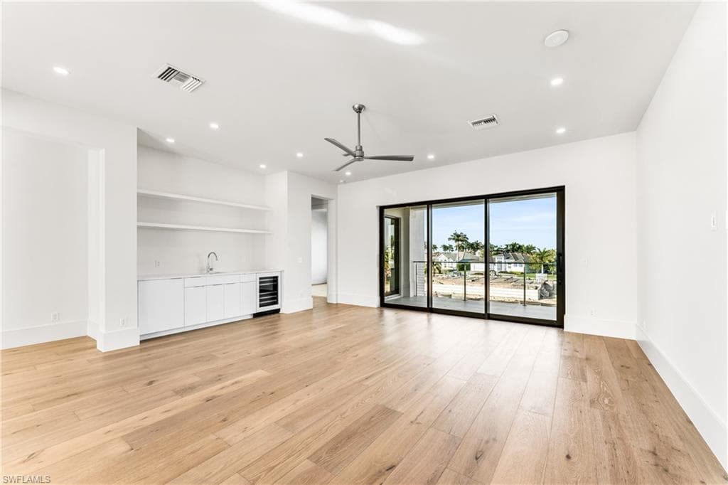 Unfurnished living room with wet bar, beverage cooler, light wood finished floors, recessed lighting, and ceiling fan