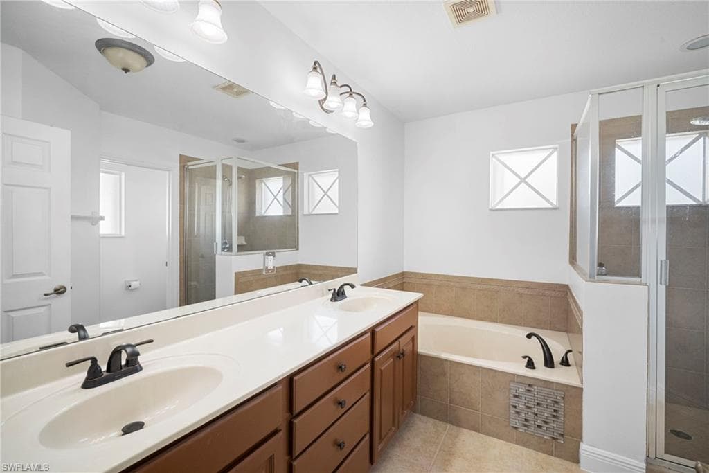 Full bath featuring plenty of natural light, a stall shower, a bath, and double vanity