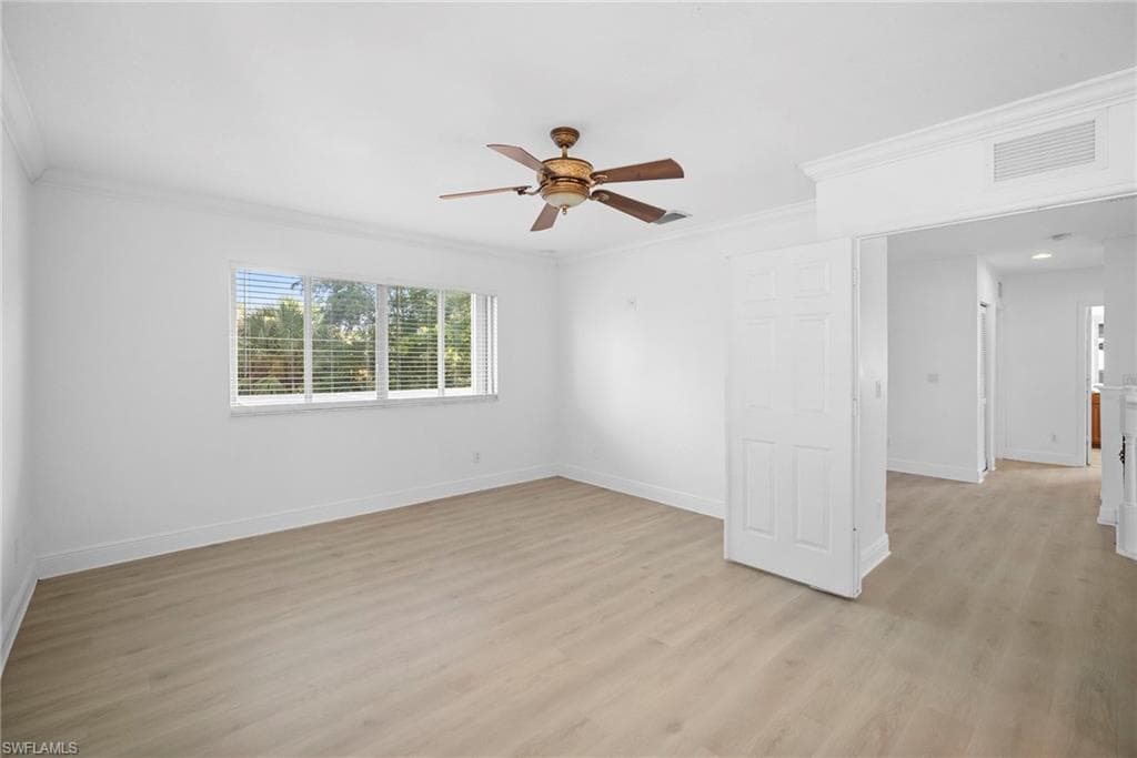 Primary bedroom room with light wood-style floors, ornamental molding, and a ceiling fan