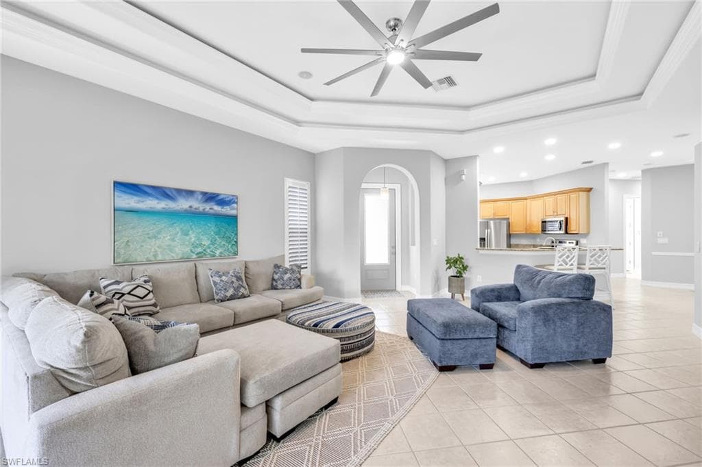 Bright, spacious, open and airy Family room featuring light tile patterned floors, ceiling fan, and a tray ceiling.