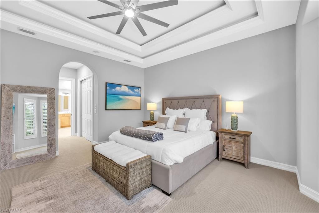 Bright and airy Primary bedroom, freshly painted, new carpet, arched walkways, a tray ceiling, and a ceiling fan