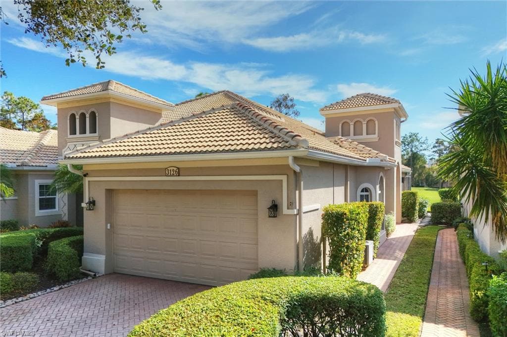 Mediterranean / spanish-style home with stucco siding, decorative driveway, and a garage