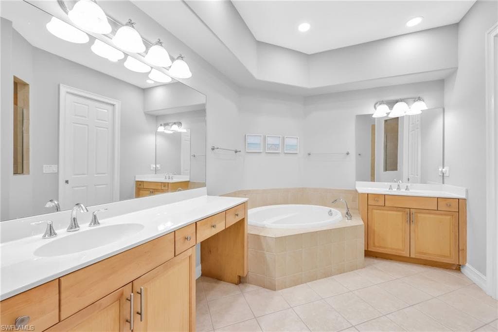 Primary bathroom with light tile patterned floors, two vanities, tub, new lighting, freshly painted