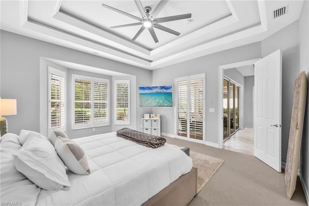 Bright and airy Primary bedroom, freshly painted, new carpet, arched walkways, a tray ceiling, and a ceiling fan