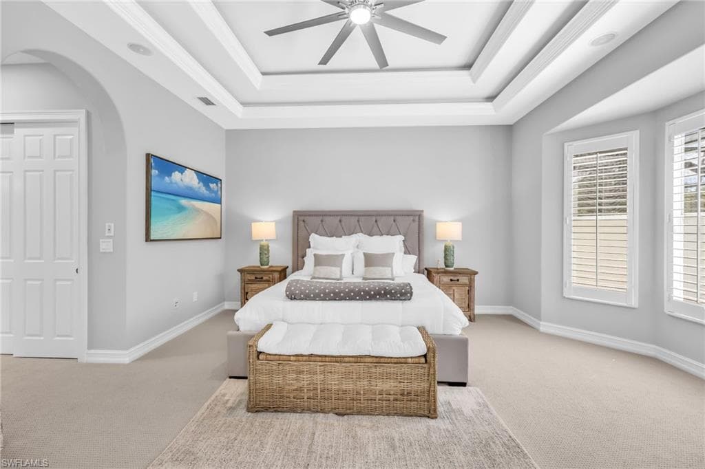 Bright and airy Primary bedroom, freshly painted, new carpet, arched walkways, a tray ceiling, and a ceiling fan