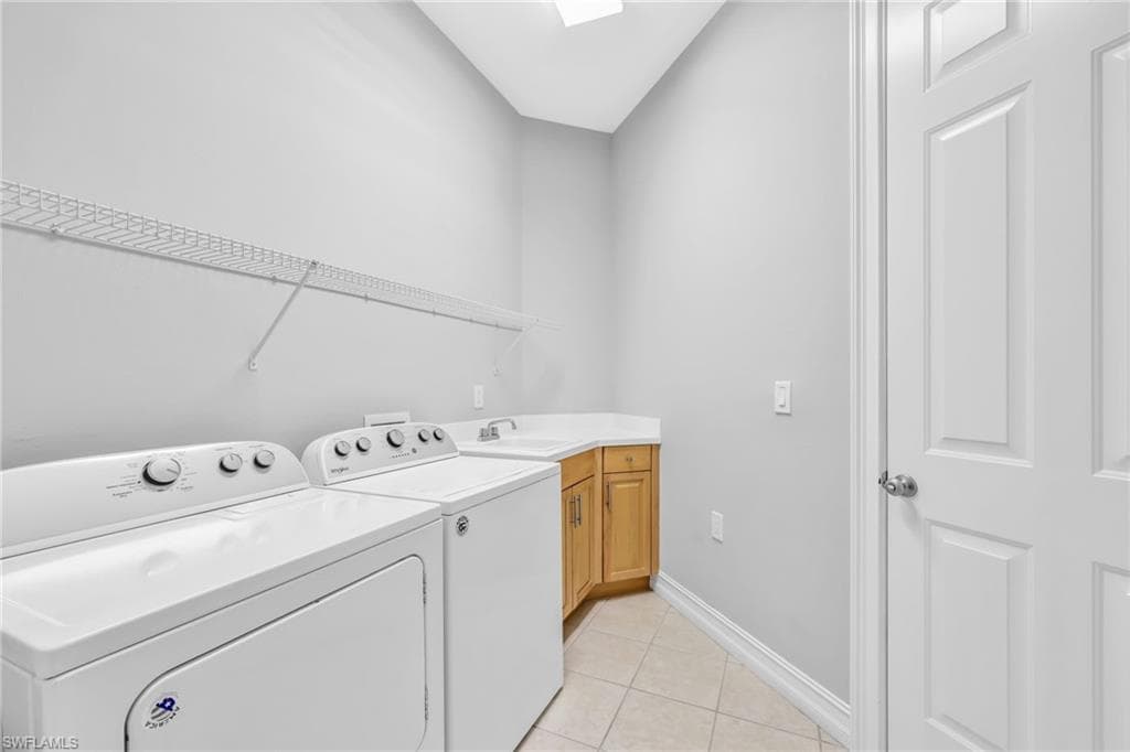 Laundry room featuring tile floors, new light, washer and dryer, sink, cabinet and shelf space