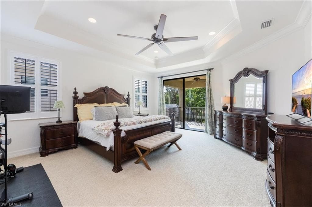 Bedroom featuring ceiling fan, light colored carpet, a raised ceiling, and access to exterior