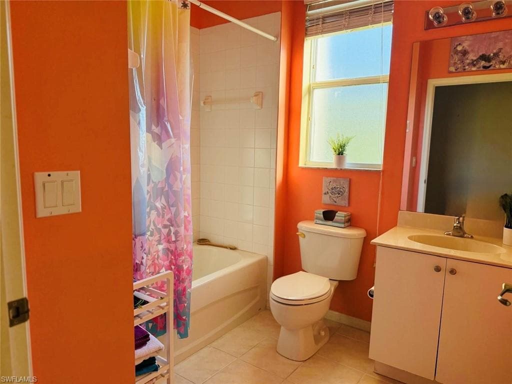 Full bathroom featuring vanity, shower / bath combination with curtain, and light tile patterned flooring