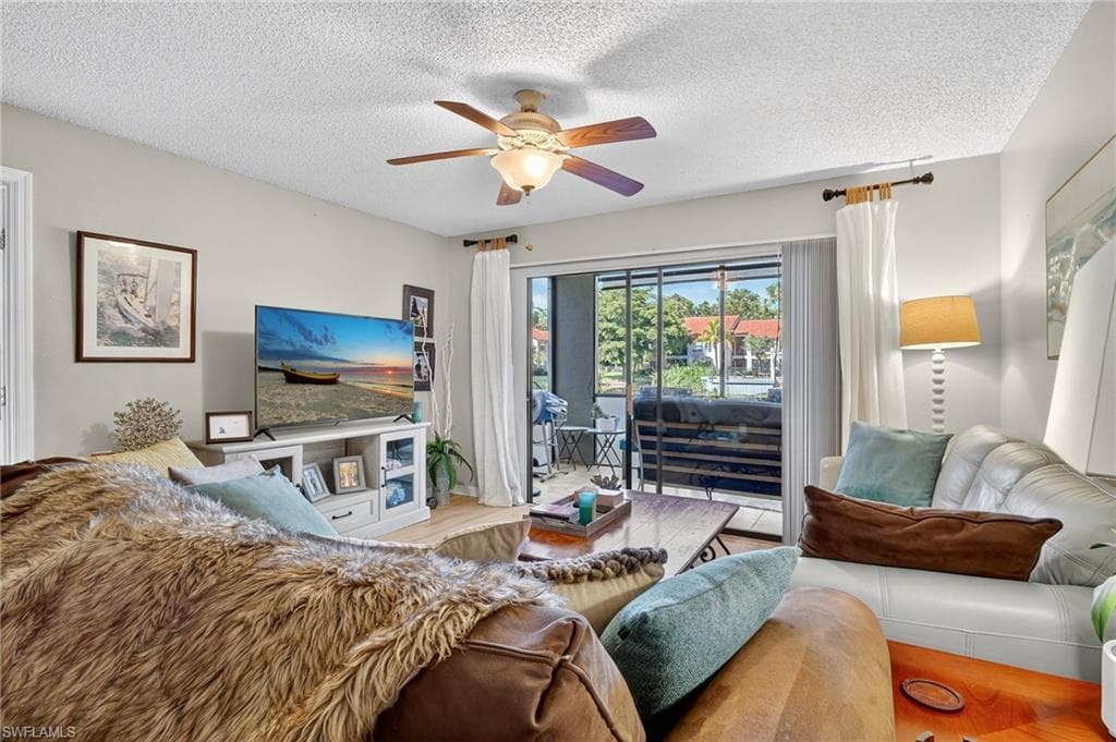 Living area with a textured ceiling, ceiling fan, and wood finished floors