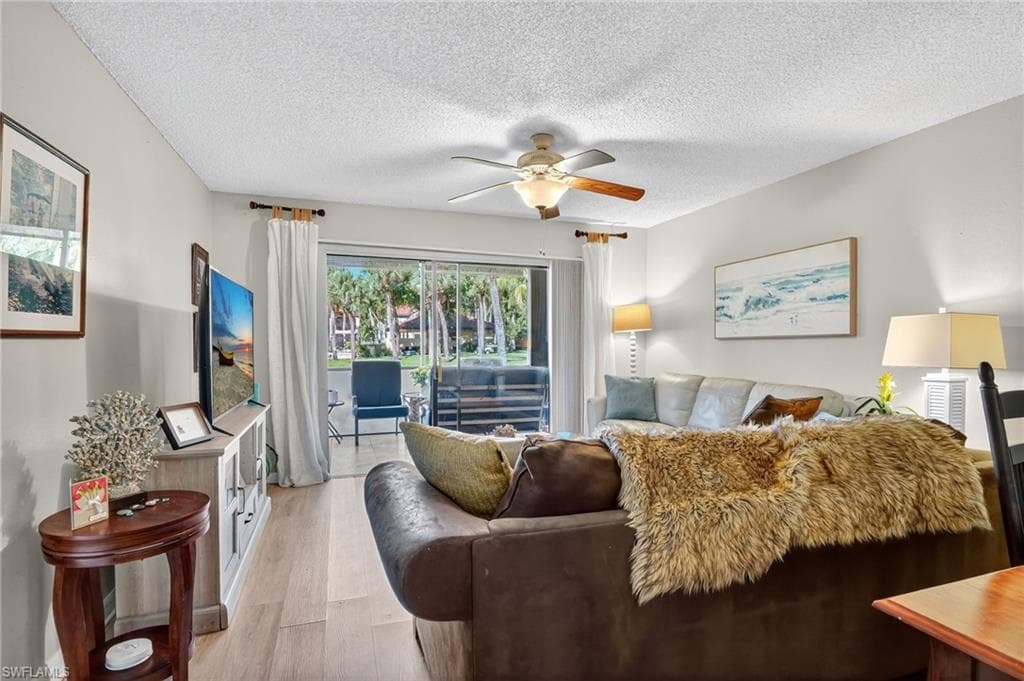 Living area with wood finished floors, a textured ceiling, and ceiling fan