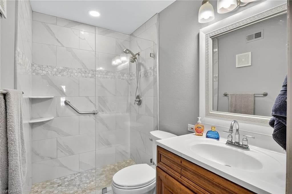 Bathroom with vanity, a stall shower, and a textured wall