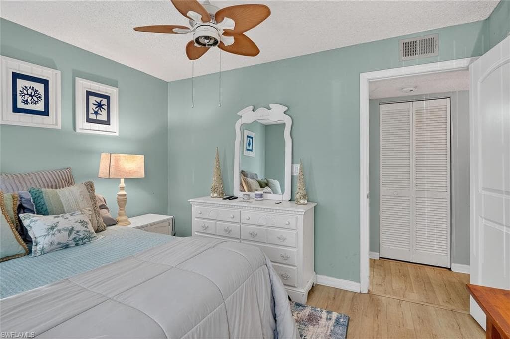 Bedroom with light wood-type flooring, a textured ceiling, and a ceiling fan