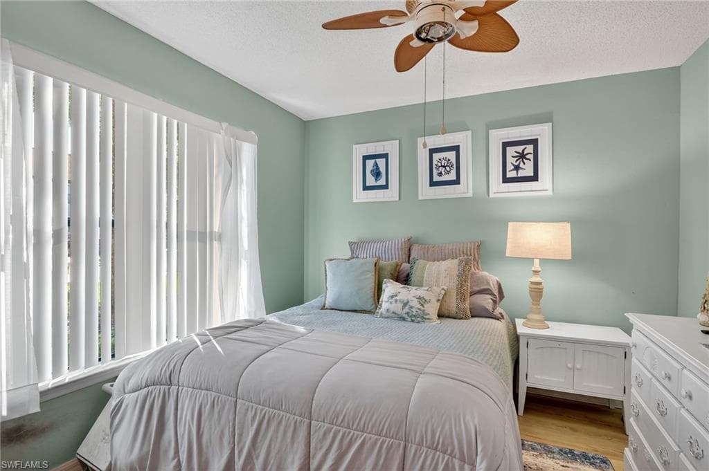 Bedroom with a textured ceiling, wood finished floors, and ceiling fan