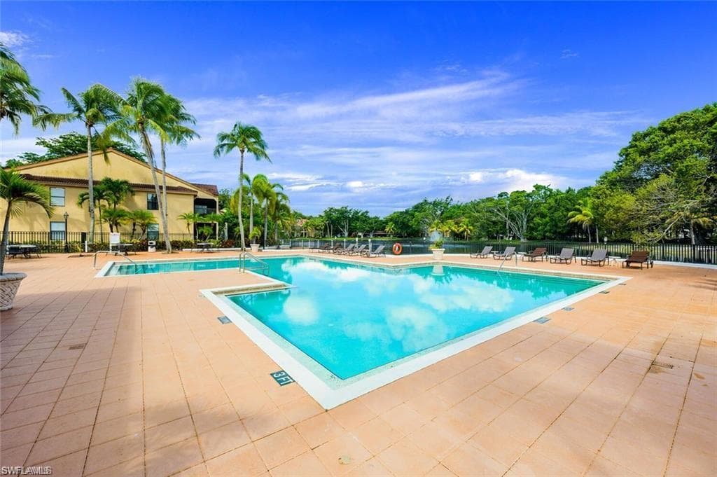 Community pool with a patio area and view of scattered trees