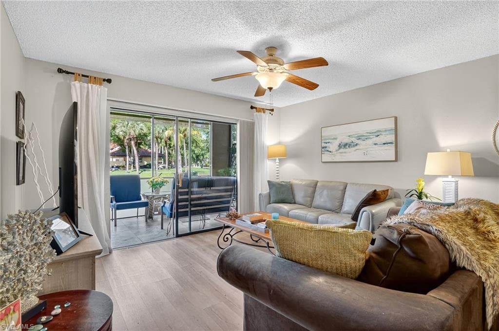 Living room with a textured ceiling, wood finished floors, and a ceiling fan