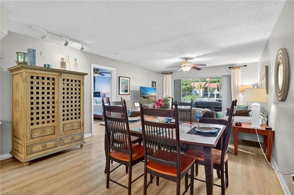 Dining area featuring light wood finished floors, a textured ceiling, and rail lighting