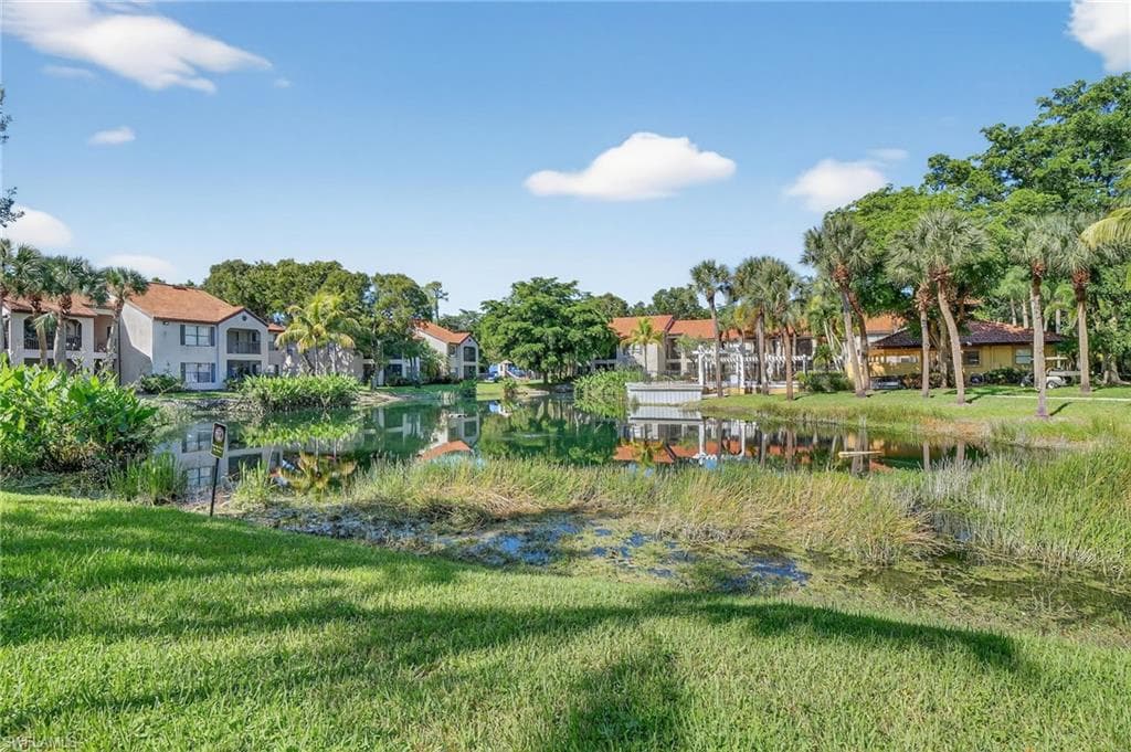 View of home's community with a water view and a lawn