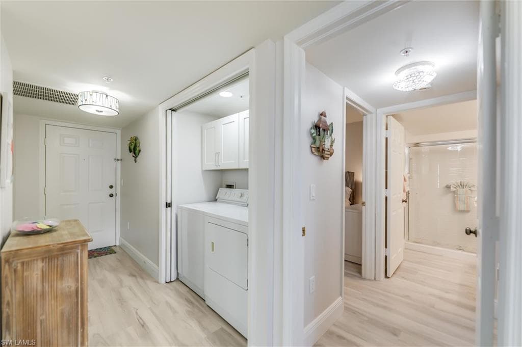Laundry area featuring light wood-style flooring, cabinet space, and separate washer and dryer