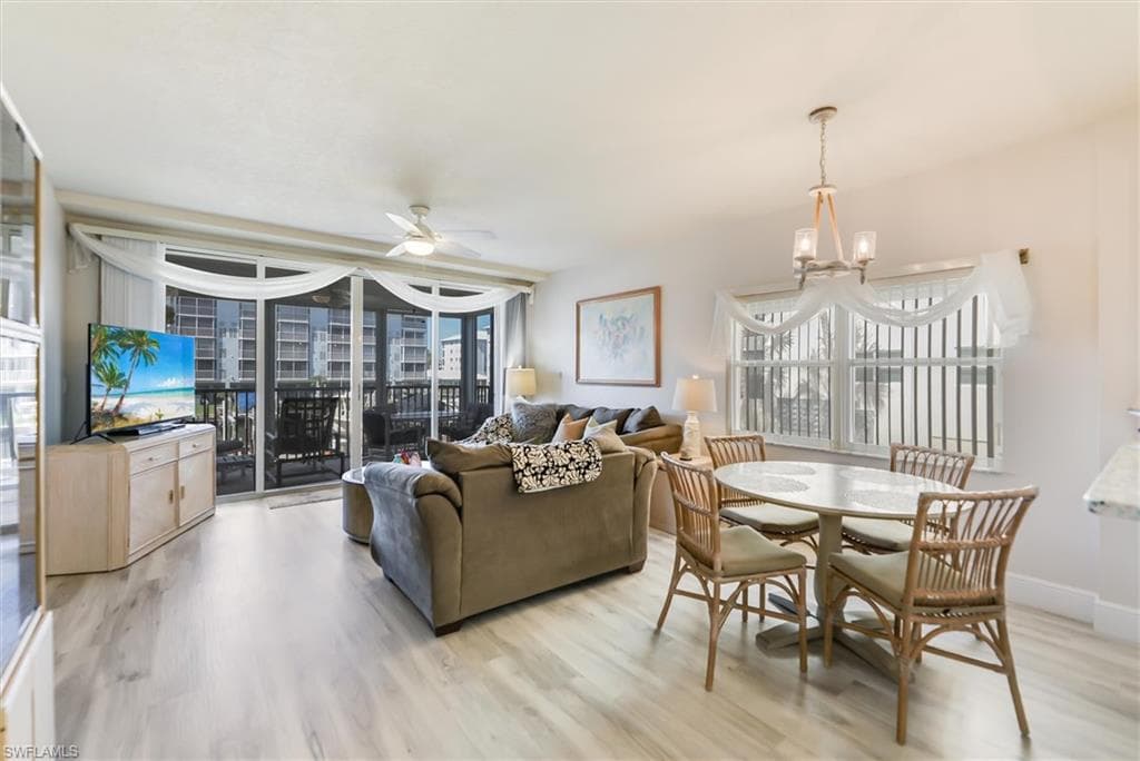 Living area featuring ceiling fan, light wood-type flooring, and a chandelier