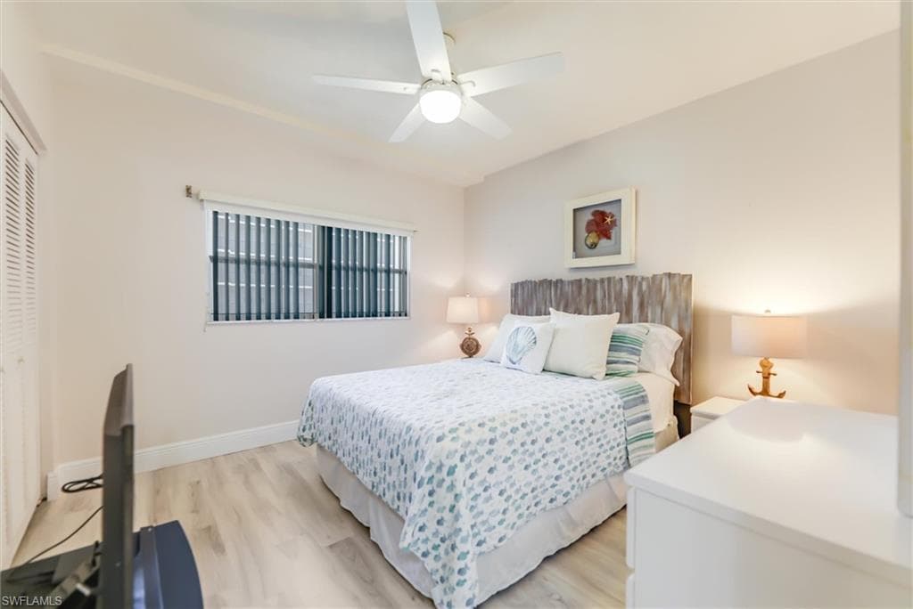 Bedroom with light wood-style flooring, ceiling fan, and a closet
