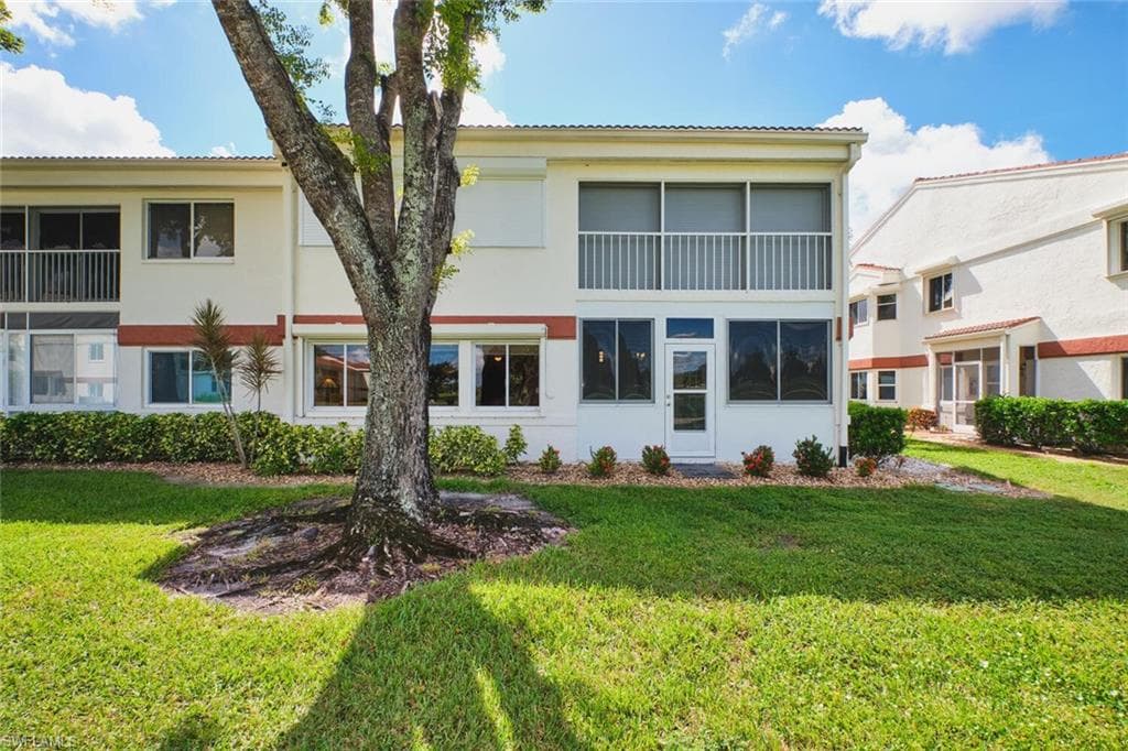 Back of property featuring a sunroom, a yard, stucco siding, and a balcony