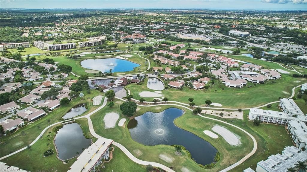 Aerial view of property's location featuring a large body of water, a golf club, and nearby suburban area