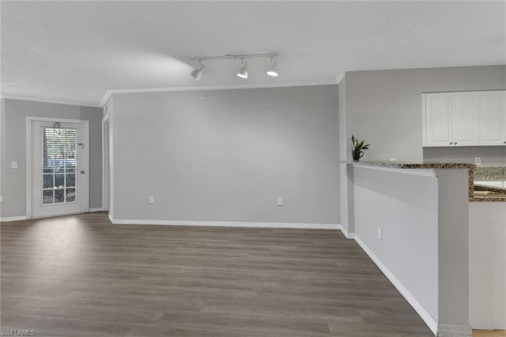 Unfurnished dining area featuring crown molding, light wood-style floors, and rail lighting