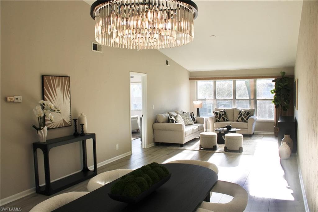 Living area featuring lofted ceiling, a chandelier, and wood finished floors