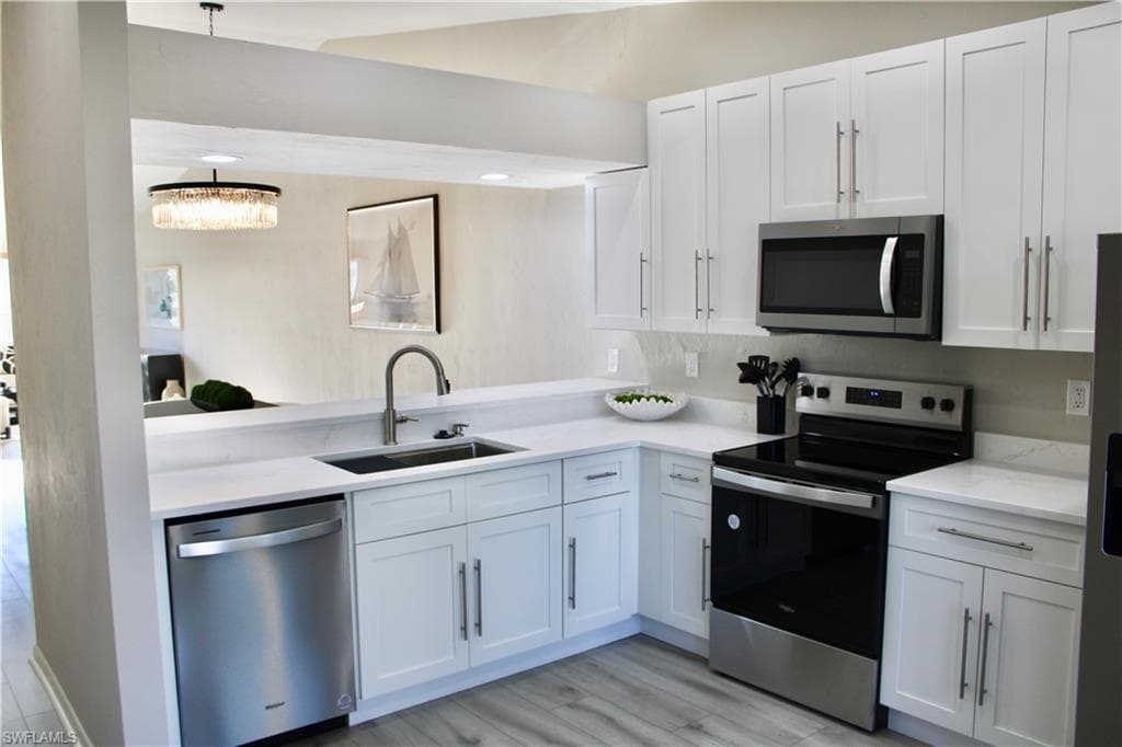 Kitchen with appliances with stainless steel finishes, white cabinets, and light wood-style flooring