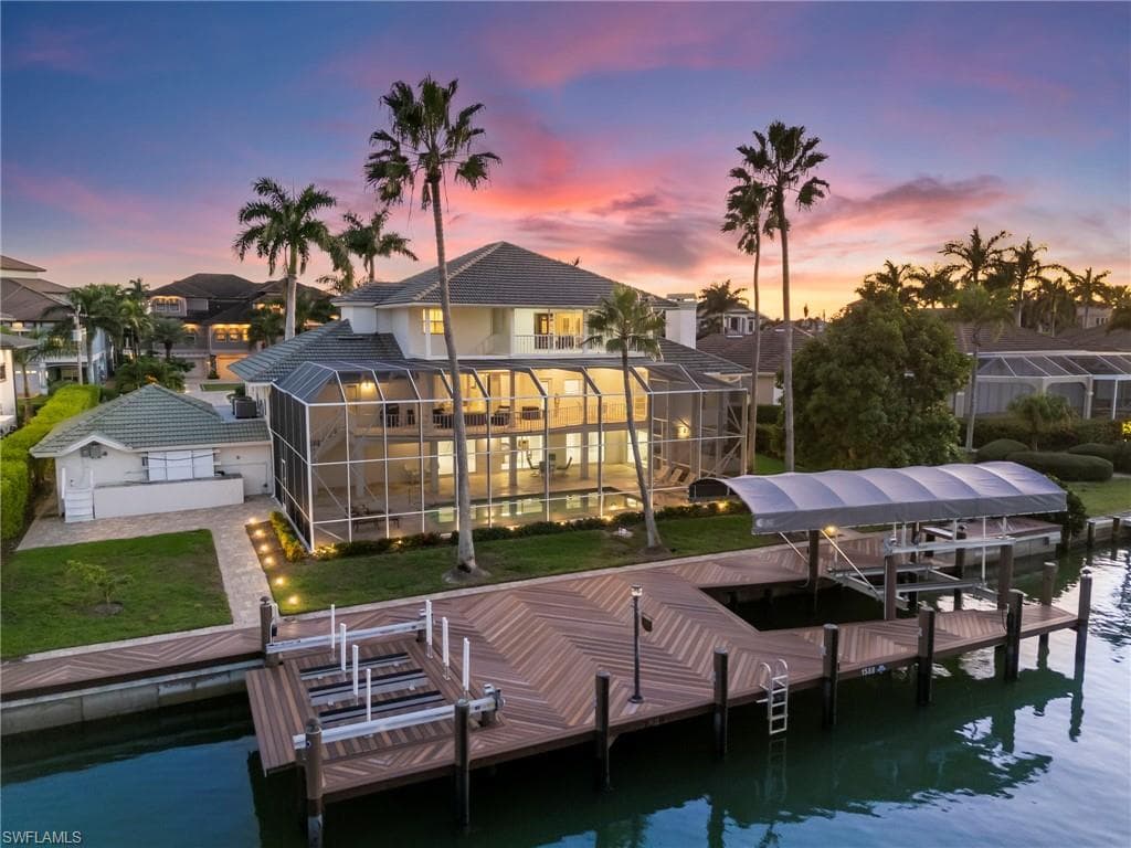 Dock featuring boat lift, a sunroom, a water view, and a lanai
