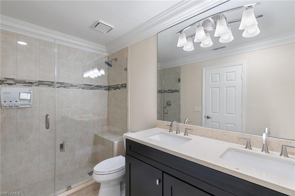 Full bath with ornamental molding, a stall shower, and double vanity