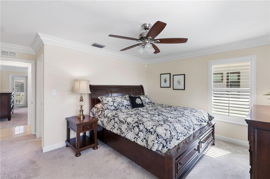 Bedroom featuring light colored carpet, crown molding, and a ceiling fan