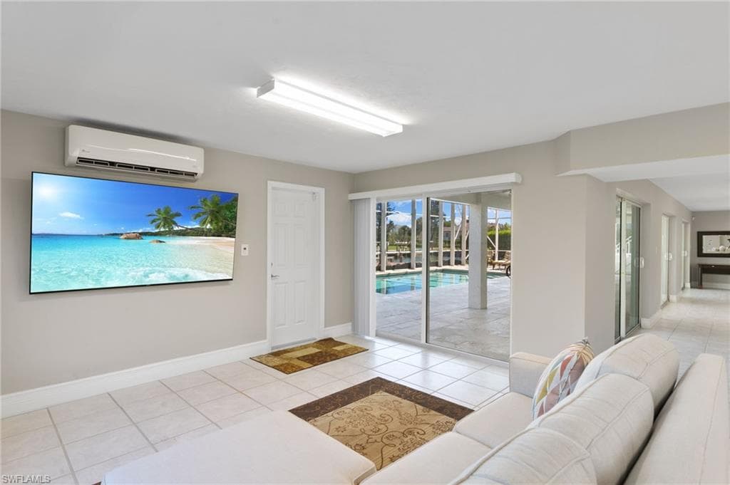 Living room with light tile patterned floors and a wall mounted air conditioner