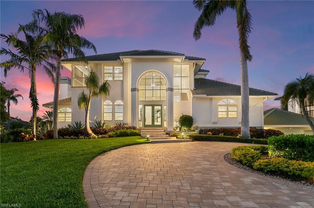Mediterranean / spanish-style house with stucco siding, a yard, french doors, and a tiled roof