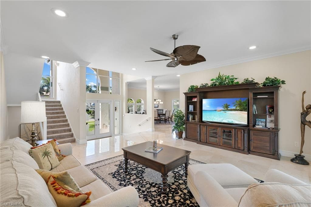 Living room featuring ornate columns, ornamental molding, recessed lighting, stairs, and a chandelier