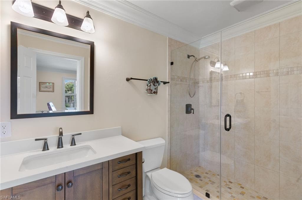 Bathroom with ornamental molding, vanity, and a shower stall