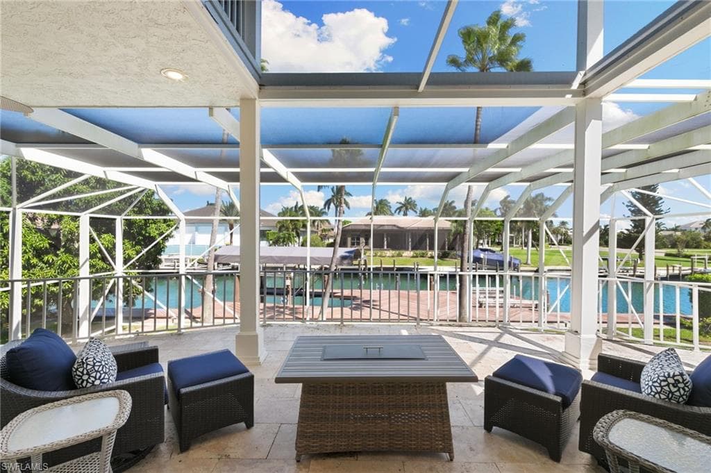 View of patio featuring a sunroom, an outdoor living space, and glass enclosure