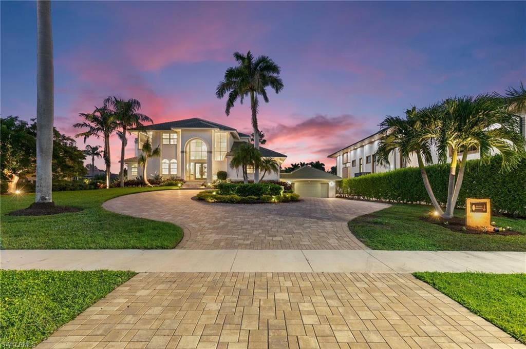 Mediterranean / spanish-style house featuring stucco siding, a front yard, decorative driveway, and a garage