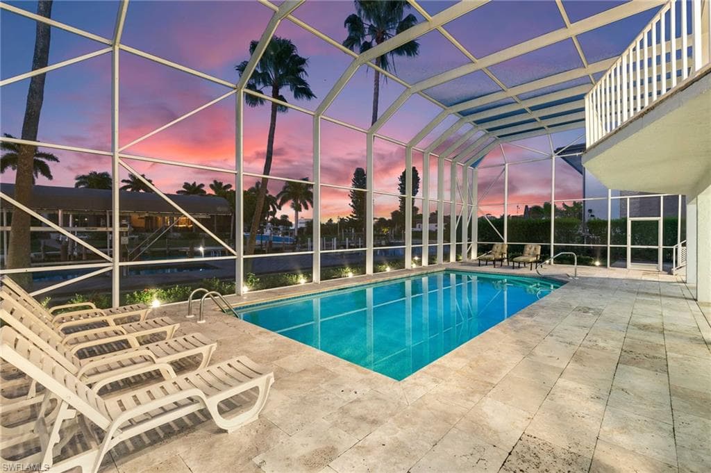 Swimming pool with a sunroom, glass enclosure, and a patio