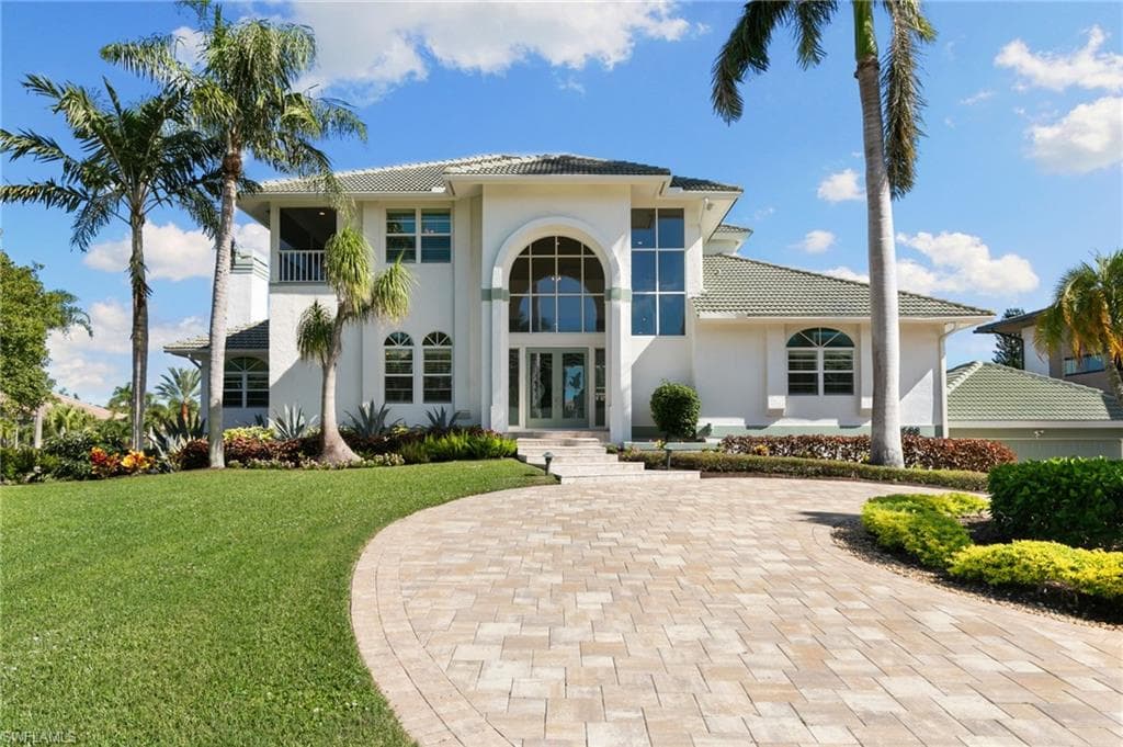 Mediterranean / spanish house with french doors, a tiled roof, a front lawn, stucco siding, and a balcony