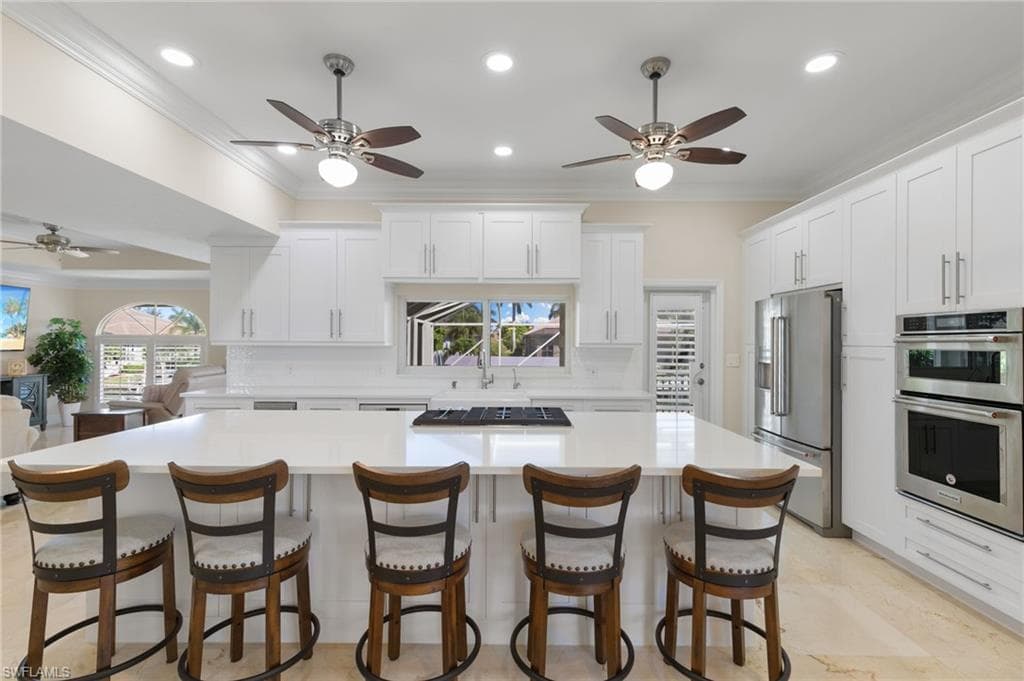 Kitchen with a center island, tasteful backsplash, white cabinetry, appliances with stainless steel finishes, and ornamental molding