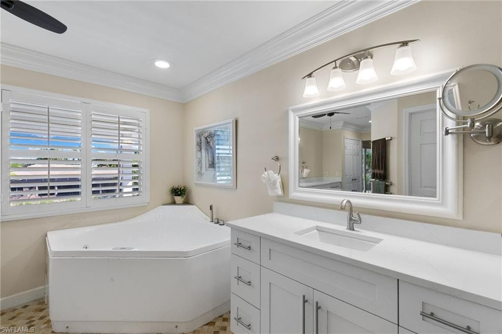 Bathroom with a ceiling fan, a garden tub, ornamental molding, vanity, and recessed lighting