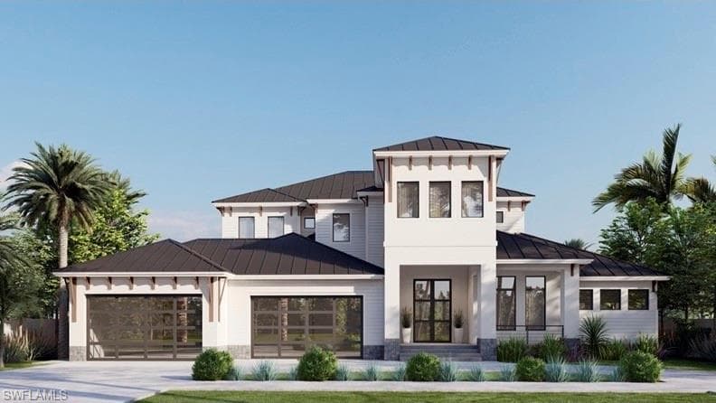View of front facade featuring a standing seam roof, a metal roof, an attached garage, driveway, and stone siding