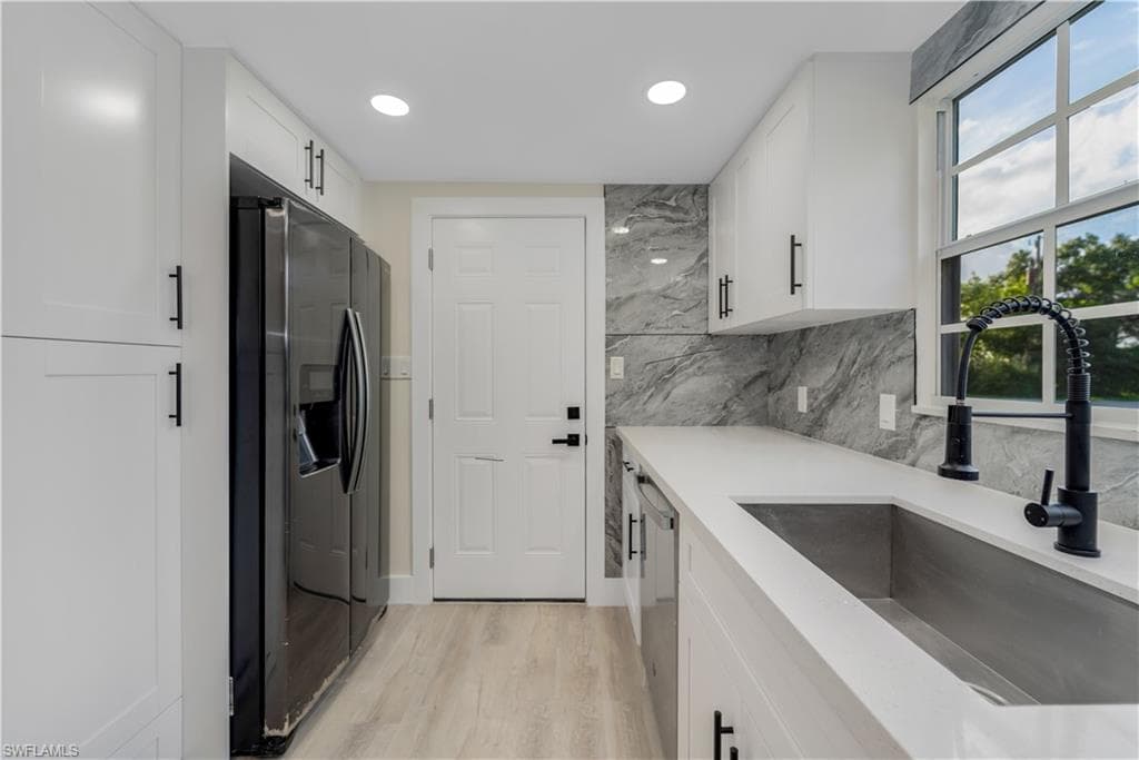 Kitchen with white cabinets, stainless steel appliances, light stone counters, decorative backsplash, and recessed lighting
