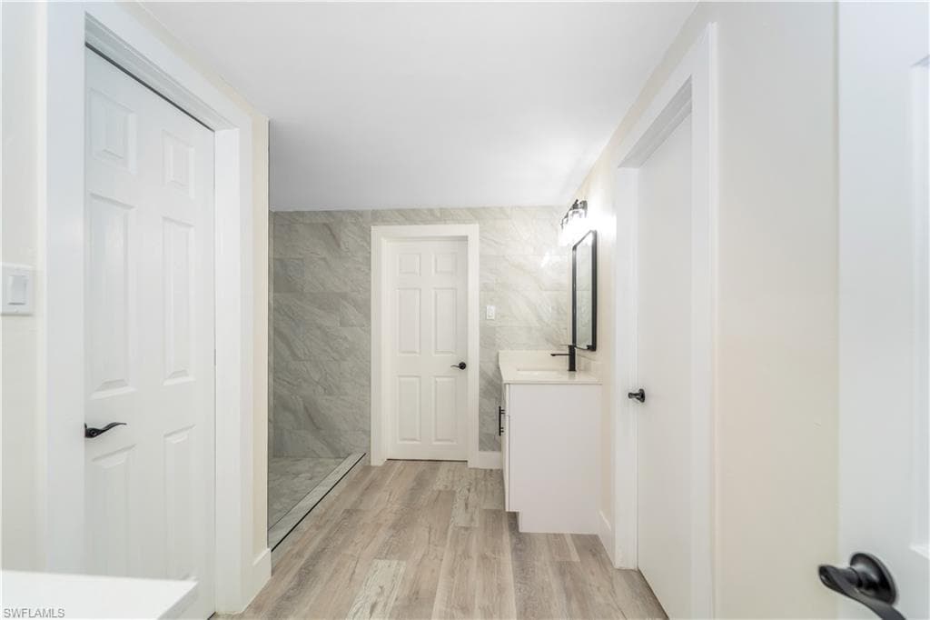 Bathroom featuring vanity, a stall shower, and light wood finished floors